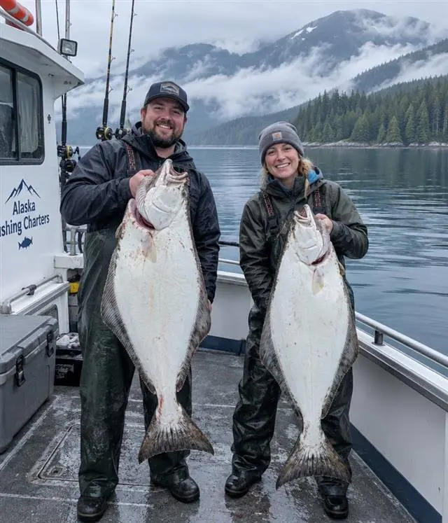 Alaska fishing charters | Alaska Coastal Hunts Anglers on the deck of an Alaskan fishing charter vessel holding halibut with coastal mountains behind